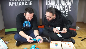 Dwóch dorosłych facetów siedzi i wypakowuje robociki Wonder Workshop